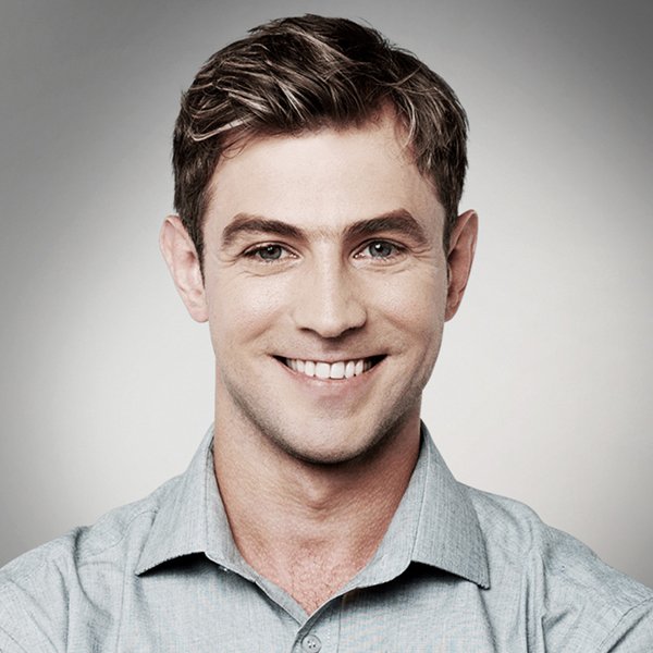 A man in a grey shirt is smiling for the camera